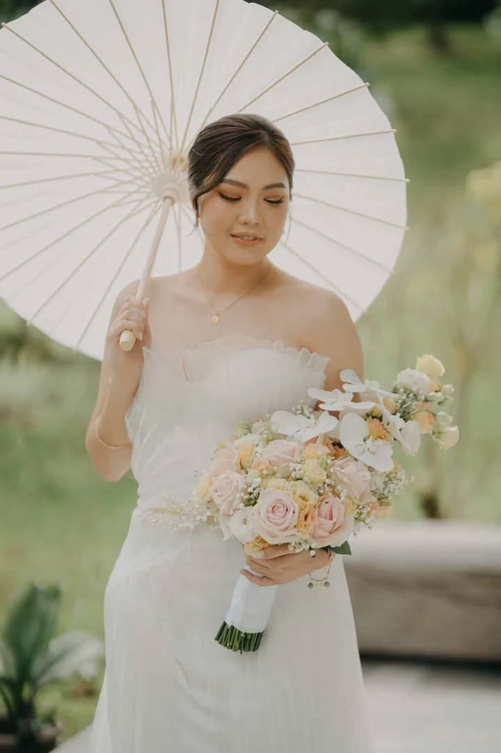 Bride in white gown holding parasol and bouquet