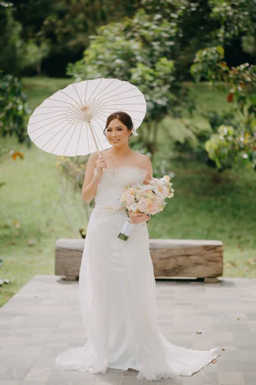 Bride in white gown with parasol outdoors