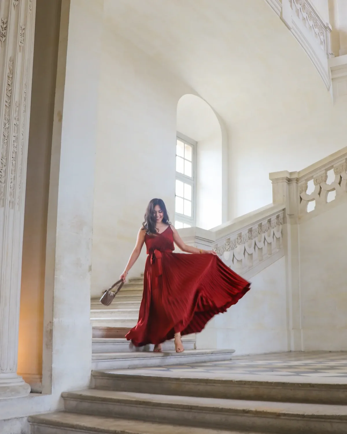 Woman in burgundy pleated dress on staircase