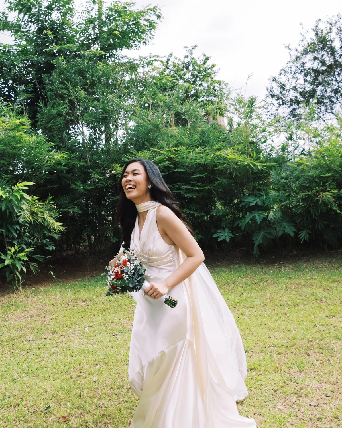 Bride in ivory gown laughing outdoors